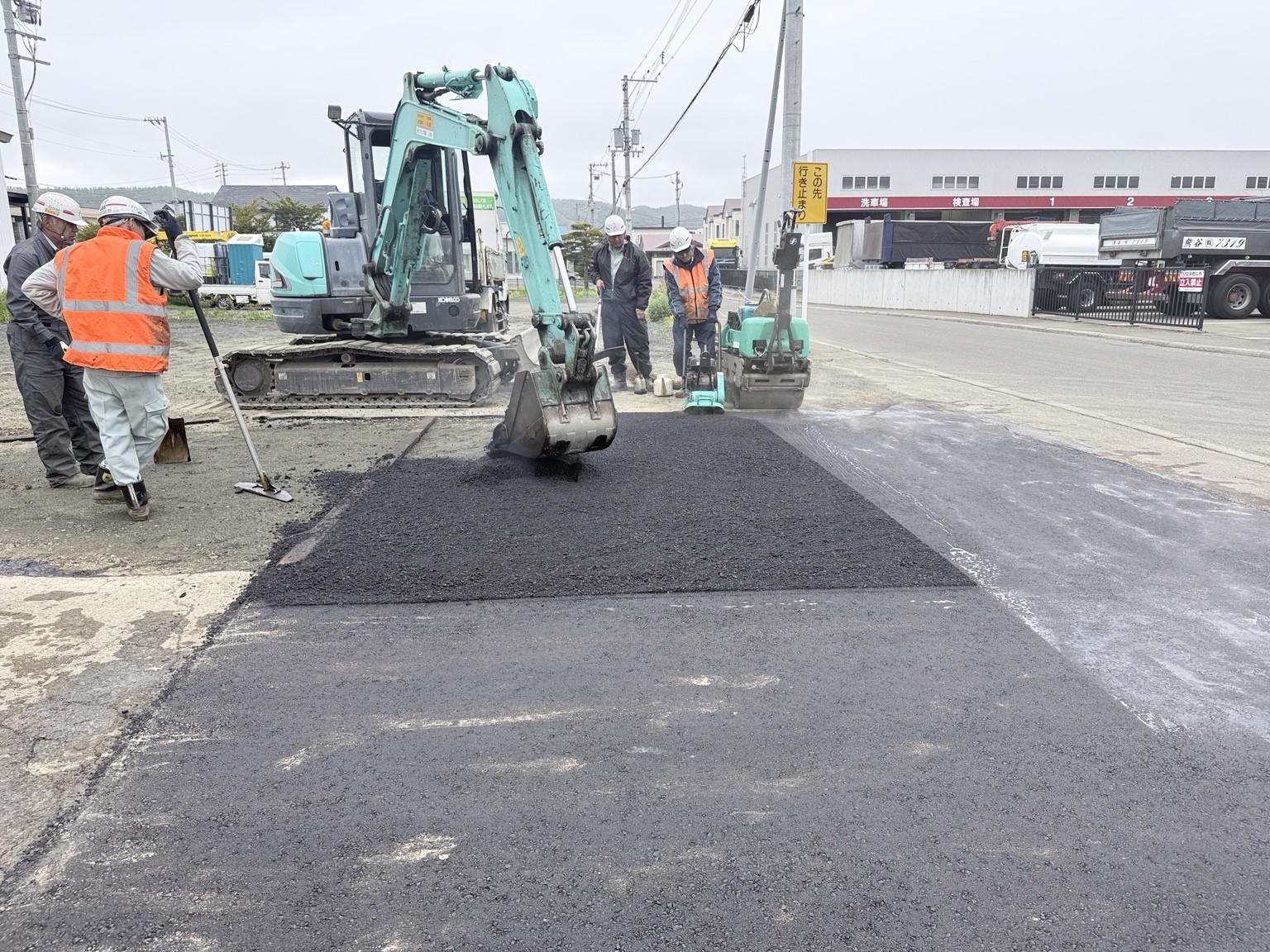 北見市で道路の舗装工事に取り組む上総工業のスタッフと重機